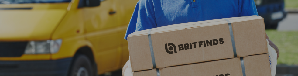 Person carrying two Brit Finds cartons with a delivery vehicle in the background, illustrating secure and efficient shipping service on Brit Finds desktop site
