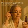 Woman applying BritFinds castor oil to her eyelashes using the included wand from the eyelash tube, with a softly blurred 100 ml castor oil bottle visible in the background 